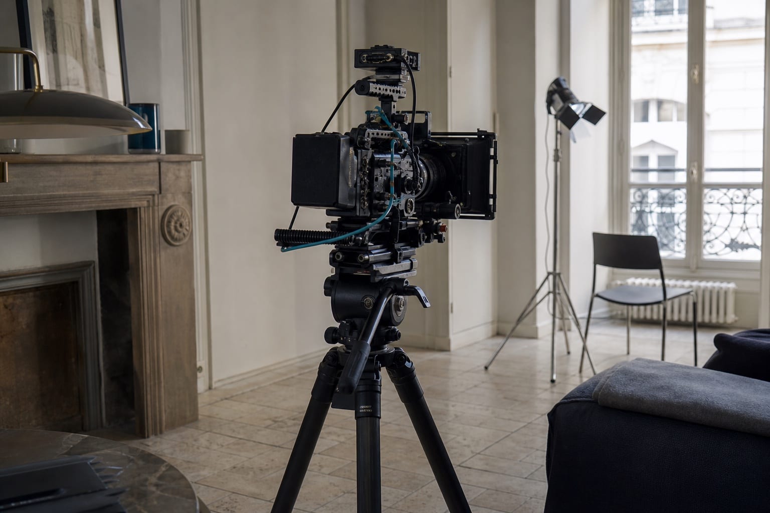 A cinema camera prepared on a tripod in a bright European interior.
